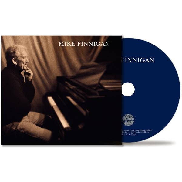 Albumcover: Mike Finnigan. Ein Mann in Gedanken sitzt in der Nähe eines Klaviers. Daneben eine CD. Dunkelblaue CD mit weißem Punkt.