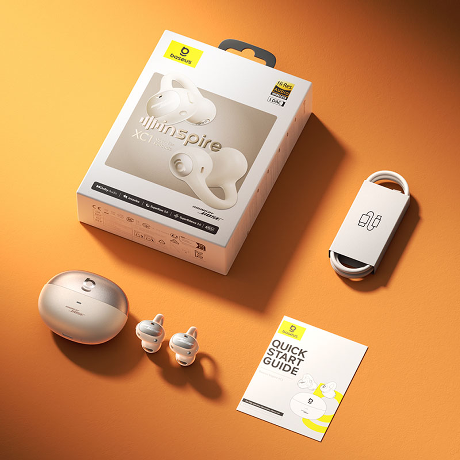 Auriculares inalámbricos Baseus, caja y accesorios sobre fondo naranja. Incluye estuche de carga, guía de inicio rápido y cable.