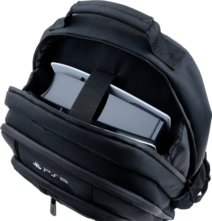 Ein schwarzer Rucksack mit einer PS5-Konsole im Inneren. Der Rucksack hat einen Griff, die PS5 wird von einem schwarzen Riemen gehalten.