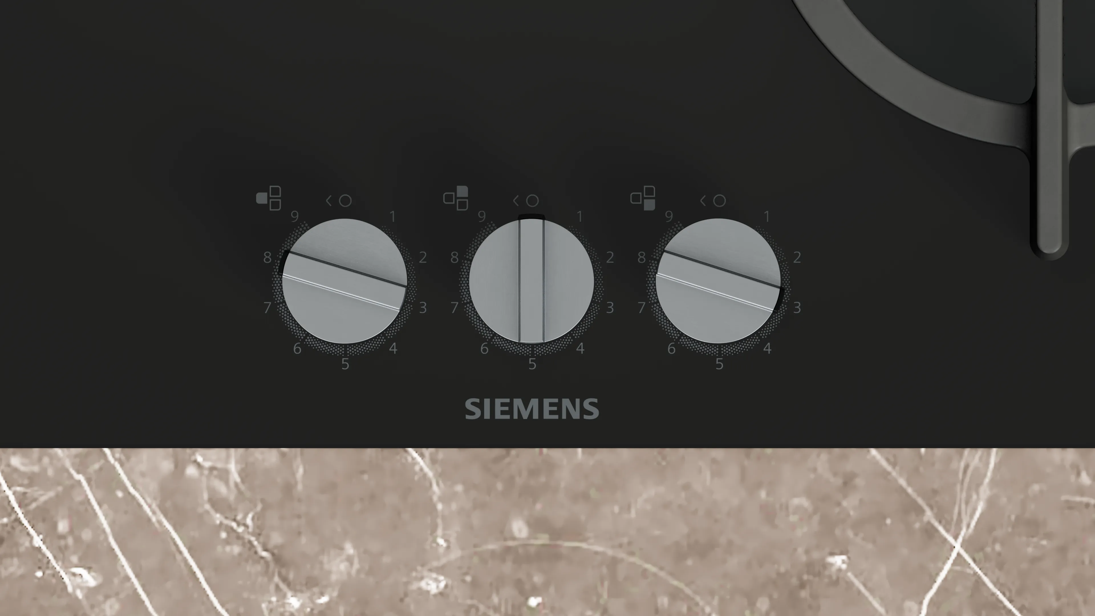 Primer plano de una encimera negra Siemens con tres mandos. El fondo es un patrón similar al mármol.