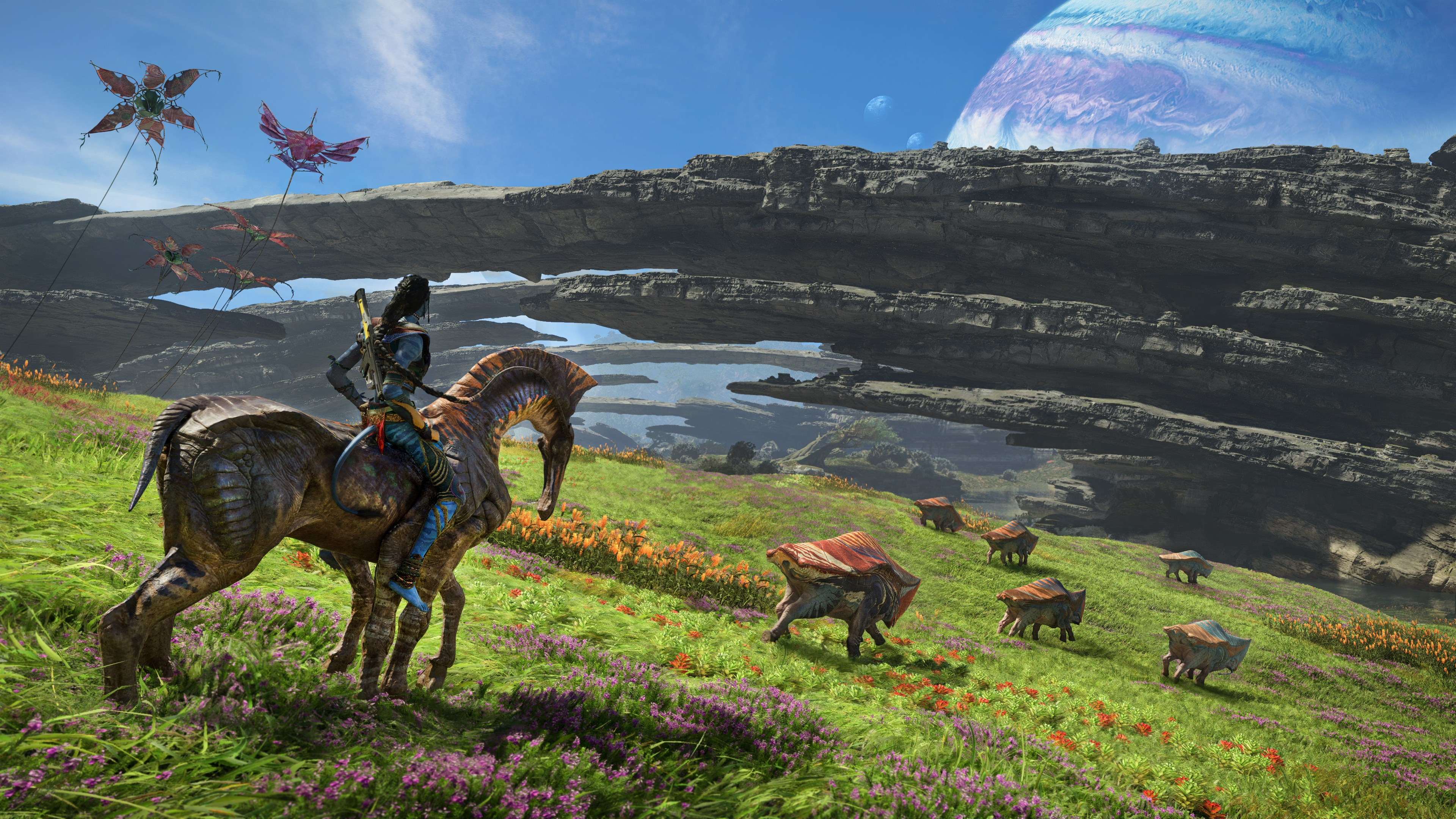 Un Na'vi cavalca una creatura simile a un cavallo su un campo colorato. Isole fluttuanti e un grande pianeta sullo sfondo. Volano aquiloni.