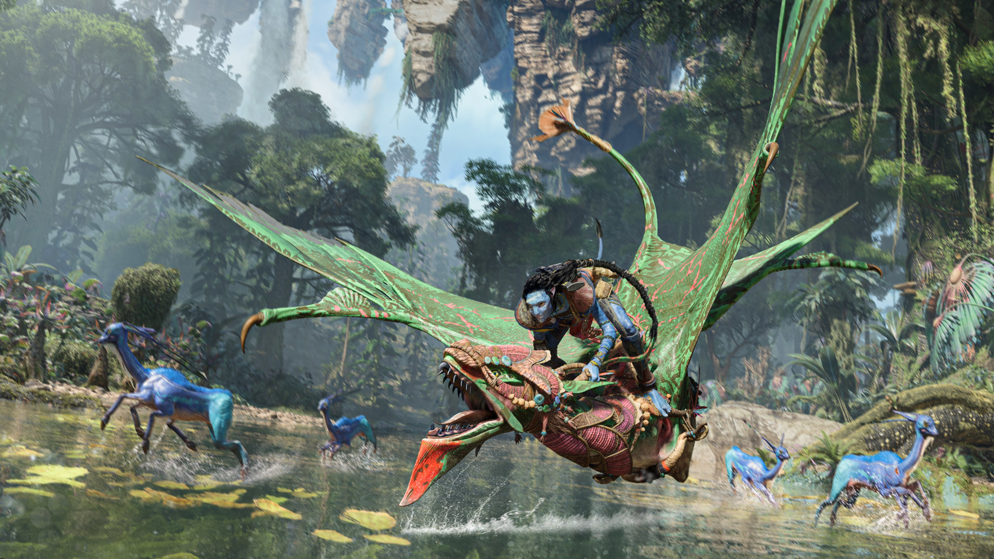 Un Na'vi cavalca una creatura alata verde e rossa. Creature blu corrono nell'acqua. La scena è una giungla lussureggiante con montagne fluttuanti.