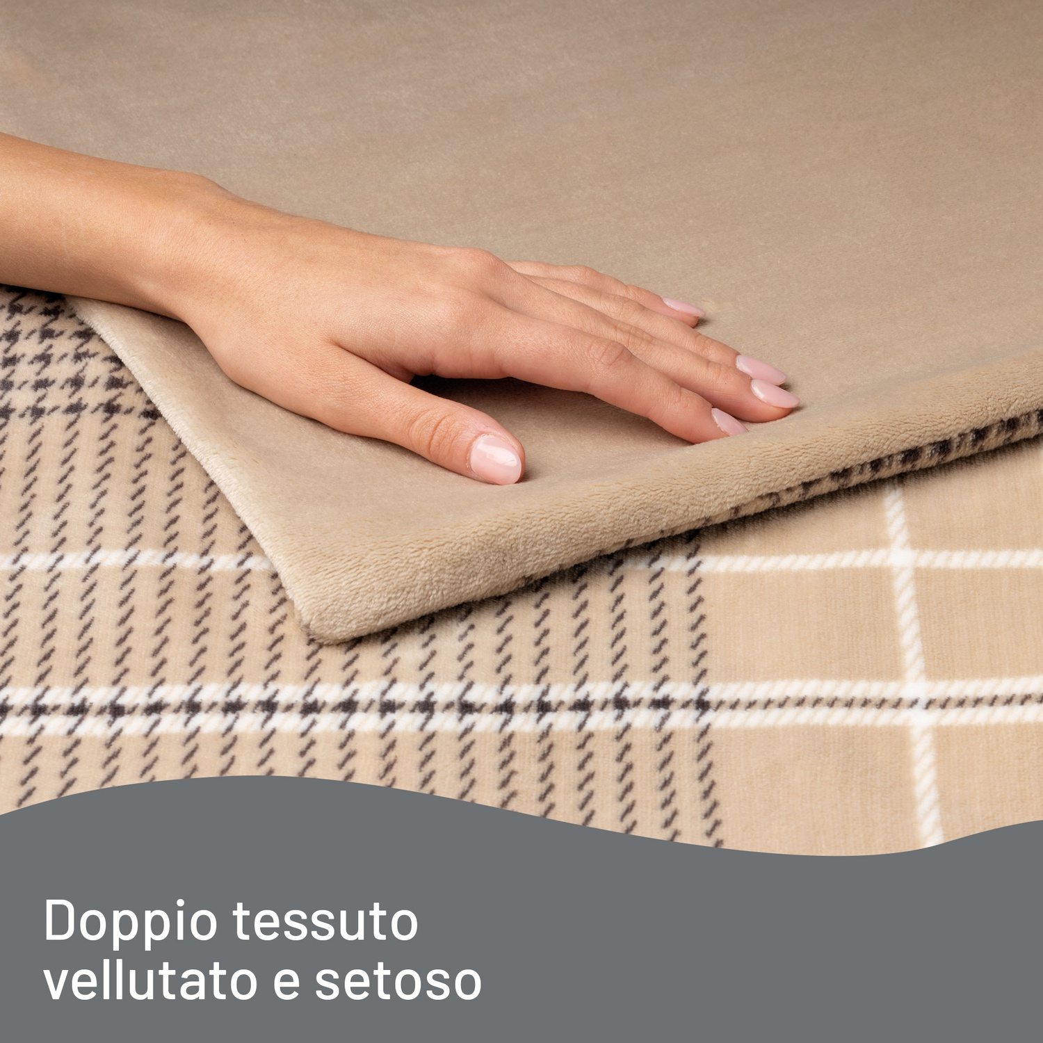 Una mano tocca una morbida coperta beige. La coperta ha un motivo a quadri sullo sfondo. Appare il testo 'Doppio tessuto vellutato e setoso'.