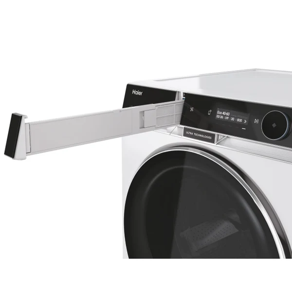 Una secadora Haier blanca con el cajón del filtro abierto. El panel de control muestra la configuración. La puerta es negra con ribete plateado.