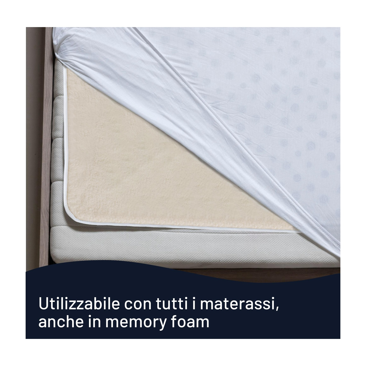 Un letto con un lenzuolo bianco che copre parzialmente un coprimaterasso beige. Il lenzuolo ha un motivo a pois.