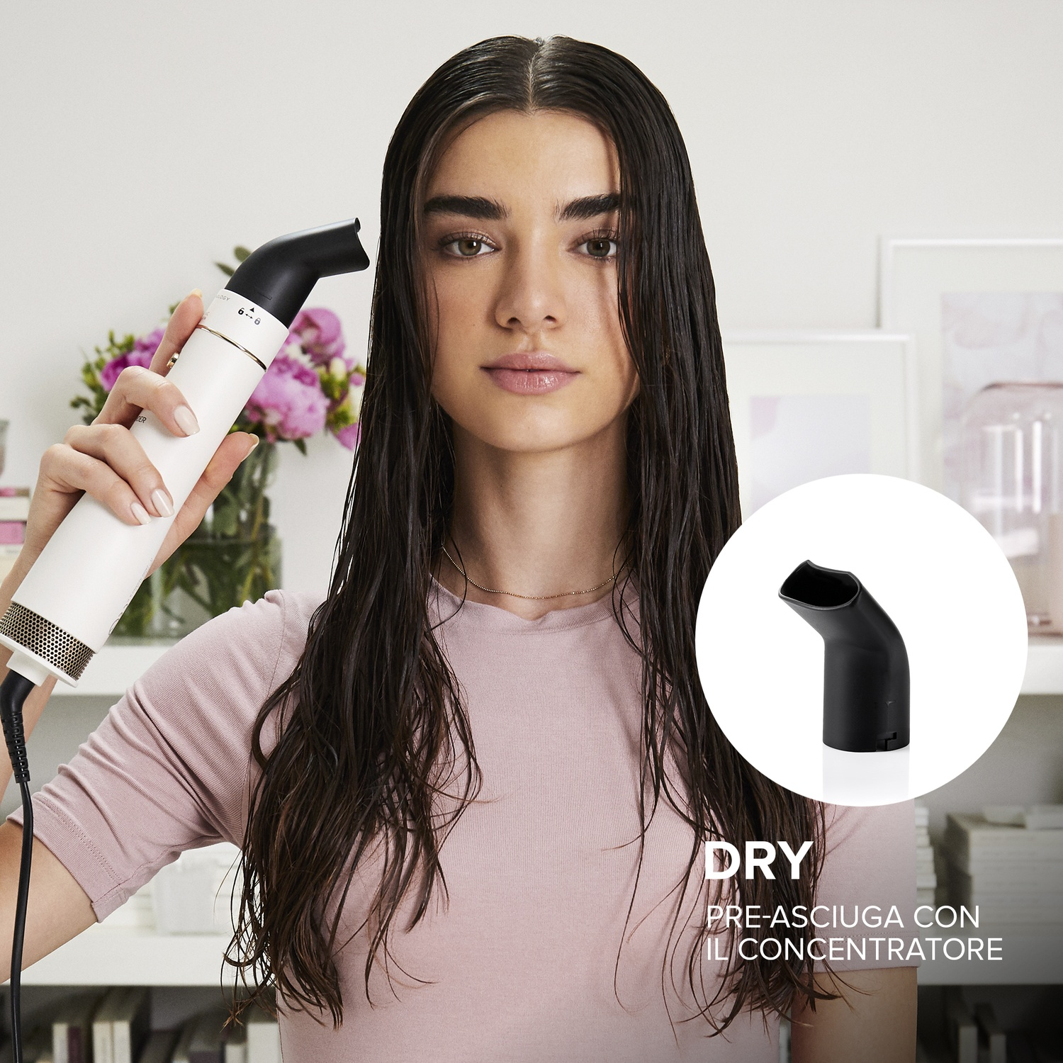 Donna che asciuga i capelli bagnati con un asciugacapelli bianco e nero. Maglietta rosa, fiori sullo sfondo.