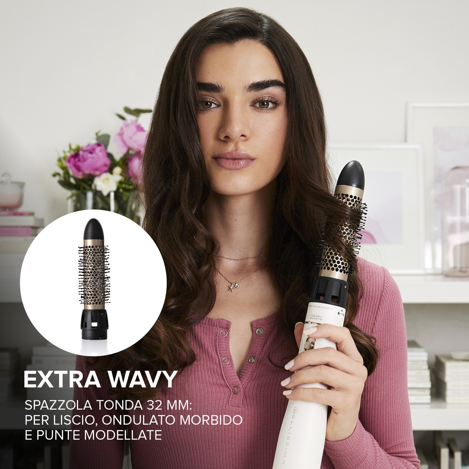 Una donna tiene una spazzola arricciacapelli, mostrando capelli mossi. Lo sfondo include fiori, una mensola e il testo 'EXTRA WAVY'.