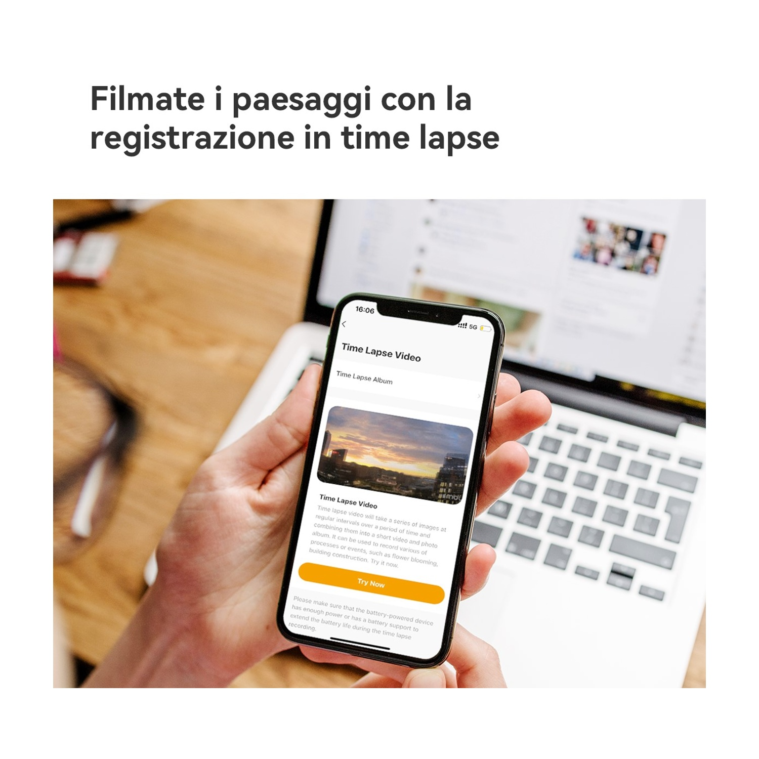 Una mano tiene in mano un telefono che mostra un'app per video in time-lapse. Un laptop è aperto sullo sfondo. La scena è in interni con una superficie in legno.