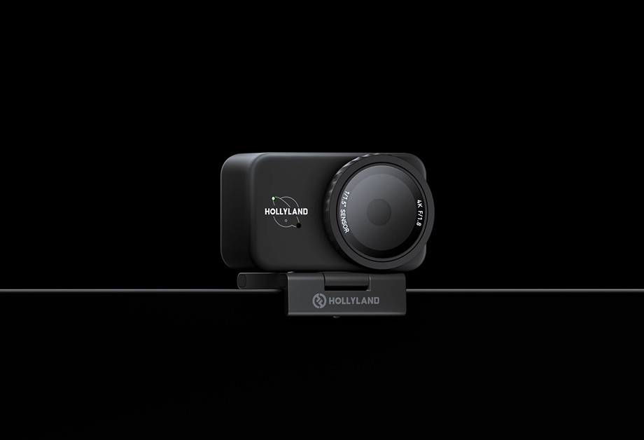 Czarna kamera Hollyland z obiektywem, zamontowana na czarnym klipsie, na czarnym tle. Widoczne logo Hollyland.