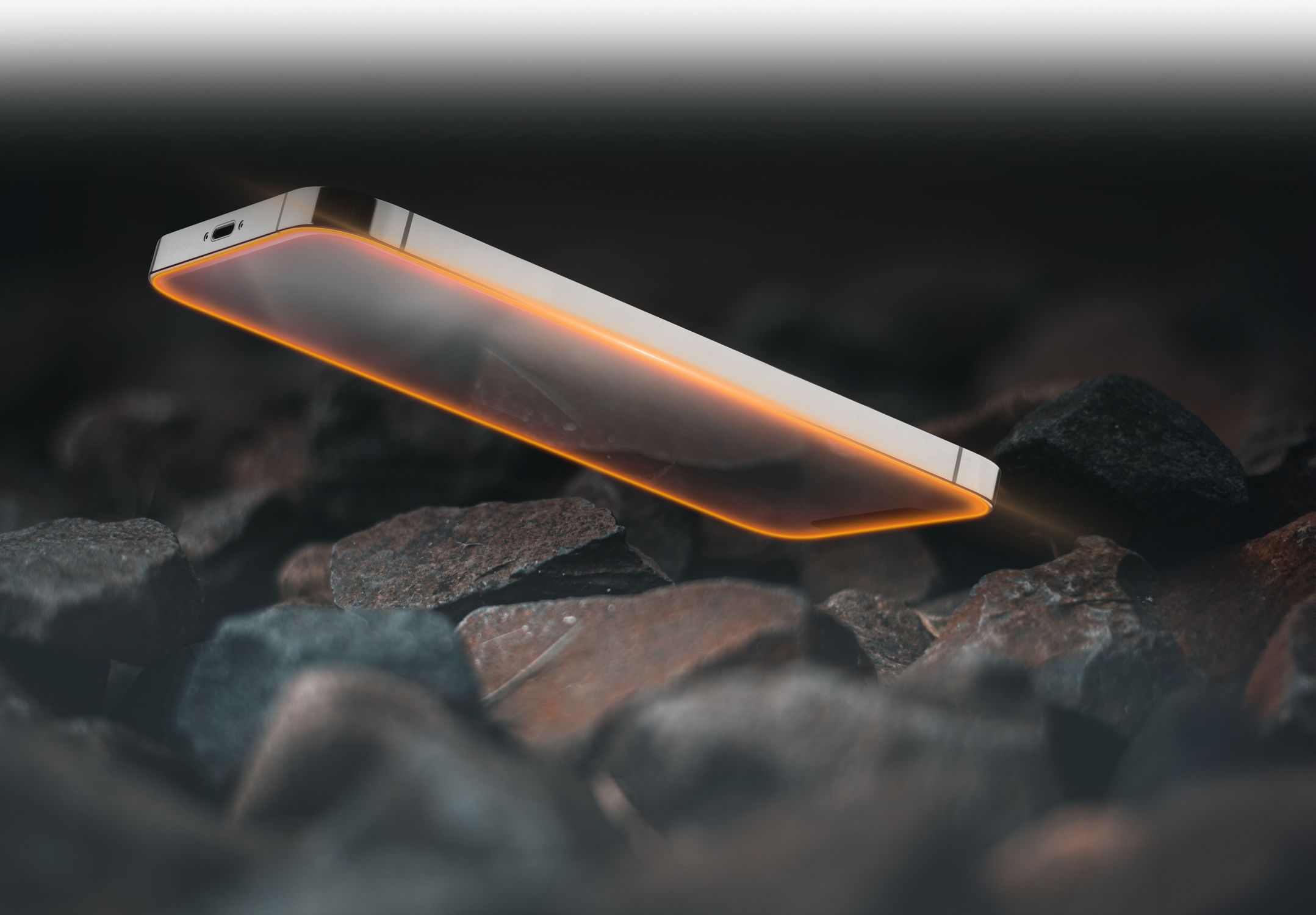 Un smartphone avec des bords orange lumineux flotte au-dessus de roches sombres. L'écran et le port de charge sont visibles.
