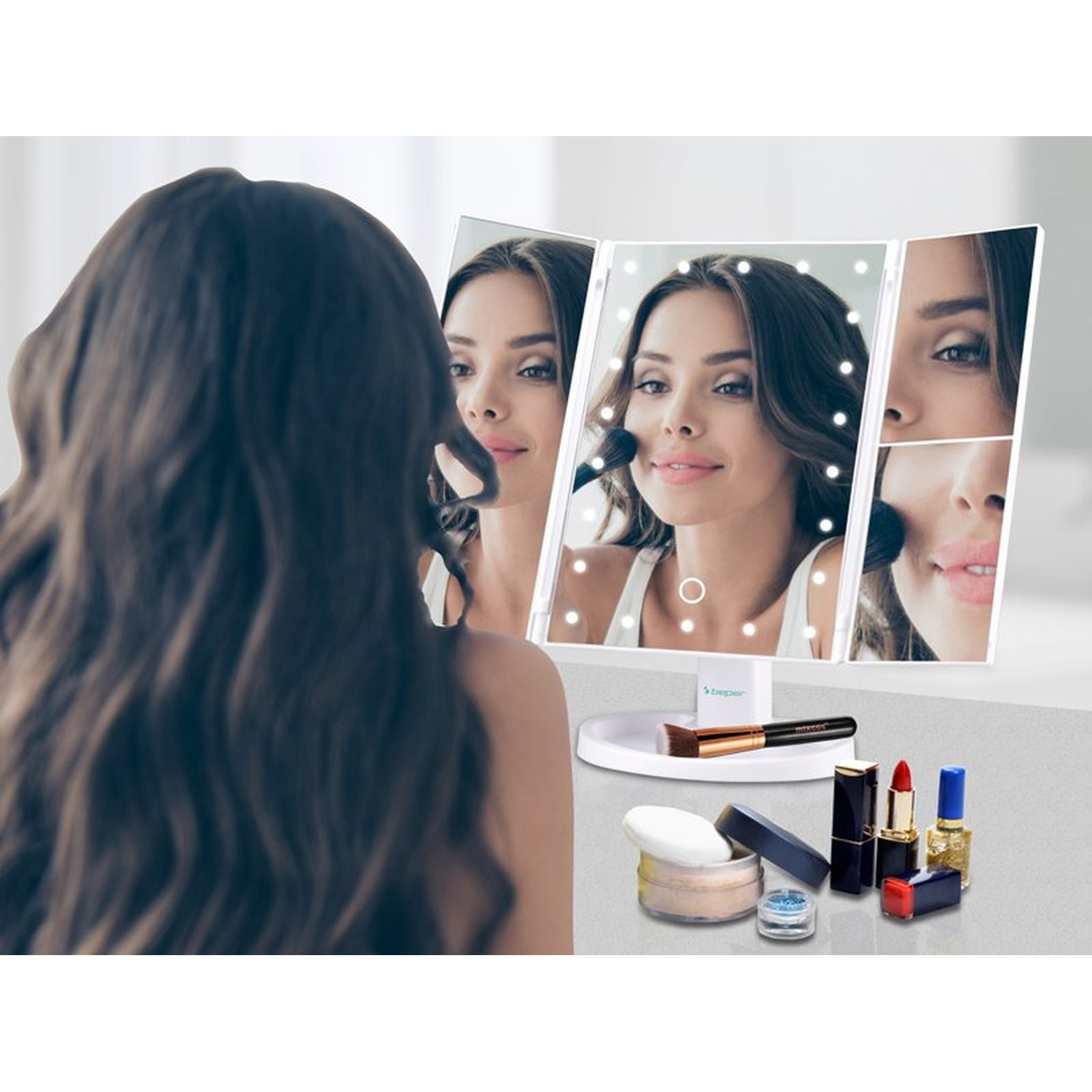 Woman applying makeup in a lighted mirror. Various cosmetics are on a table: powder, brushes, lipstick, nail polish.