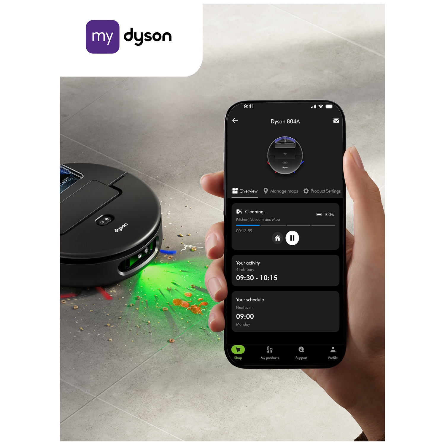 A hand holds a phone showing the Dyson 804A app. A black robot vacuum cleaner emits green light. The my dyson logo is visible.