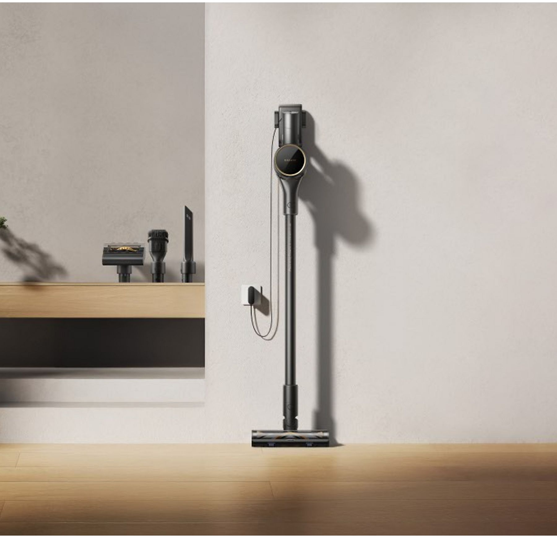 Un aspirapolvere nero e oro contro un muro bianco. Accessori aggiuntivi su una superficie di legno.