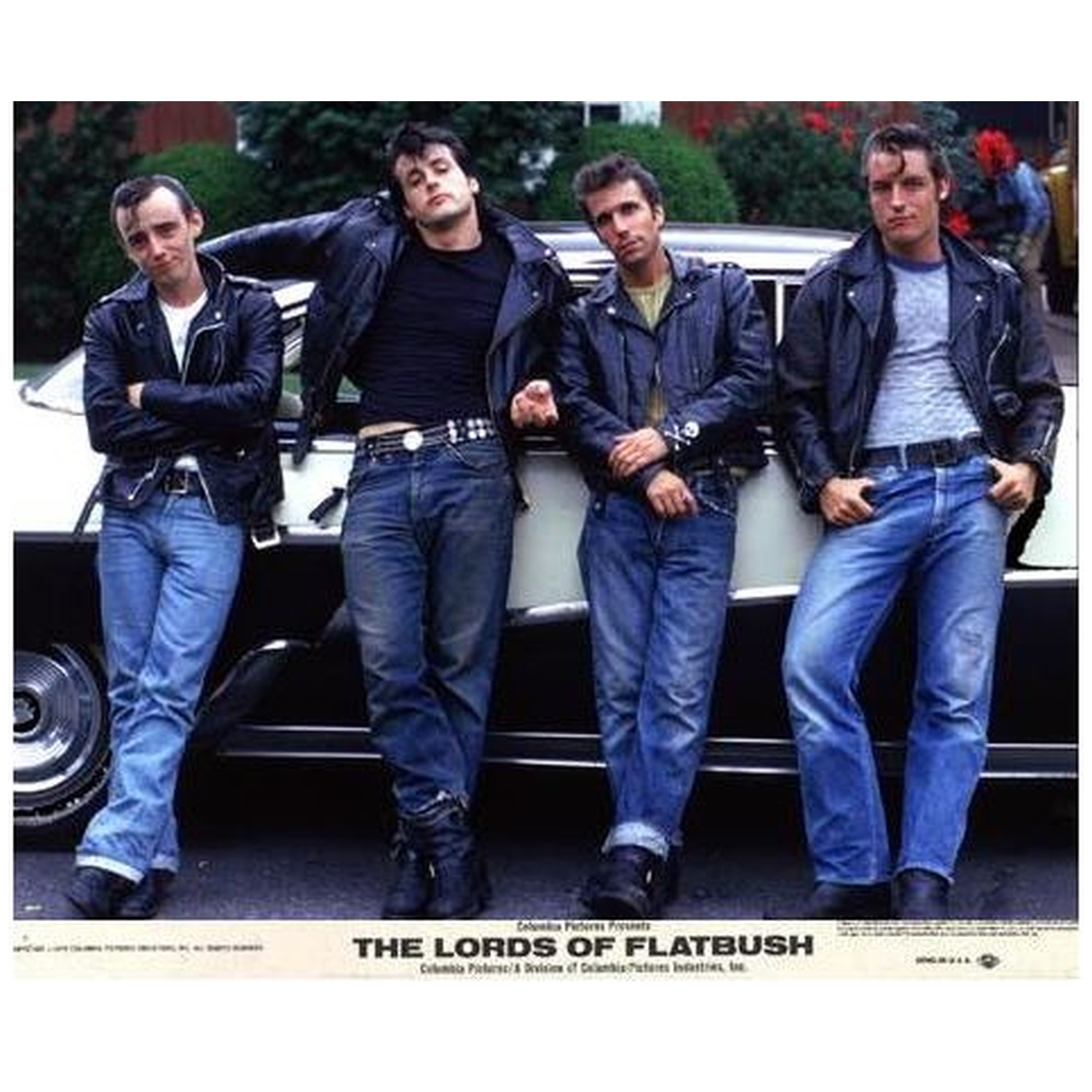 Quatre hommes en blousons de cuir et jeans s'appuient sur une voiture. Le titre 'The Lords of Flatbush' est en bas.