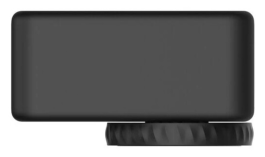 Czarny prostokątny przedmiot spoczywa na teksturowanej, okrągłej podstawie. Urządzenie jest gładkie i bez cech.