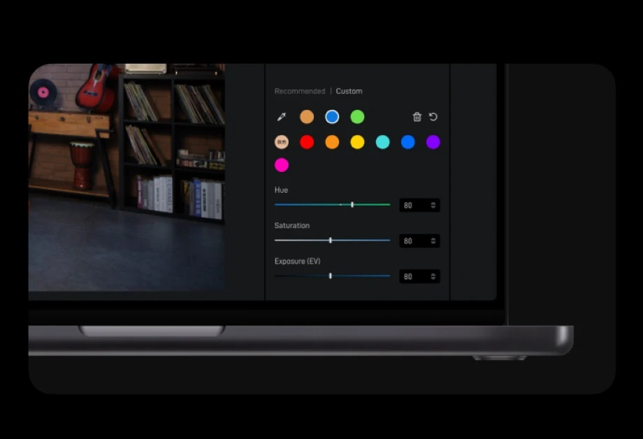 Ekran laptopa z narzędziami do regulacji kolorów. Tło przedstawia pokój z półką, płytami i gitarą.