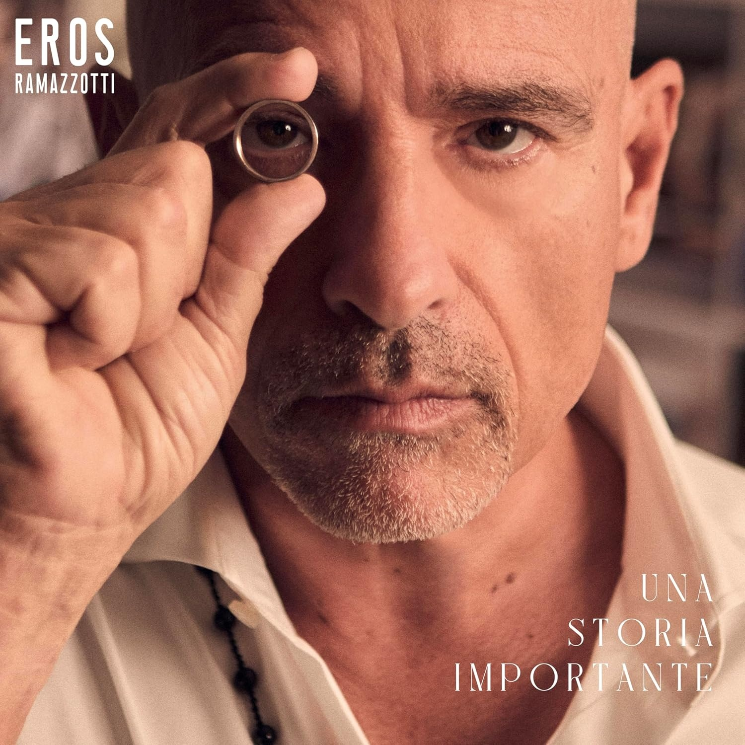 Un homme tient une bague devant son œil. Pochette d'album avec texte « EROS RAMAZZOTTI » et « UNA STORIA IMPORTANTE ».