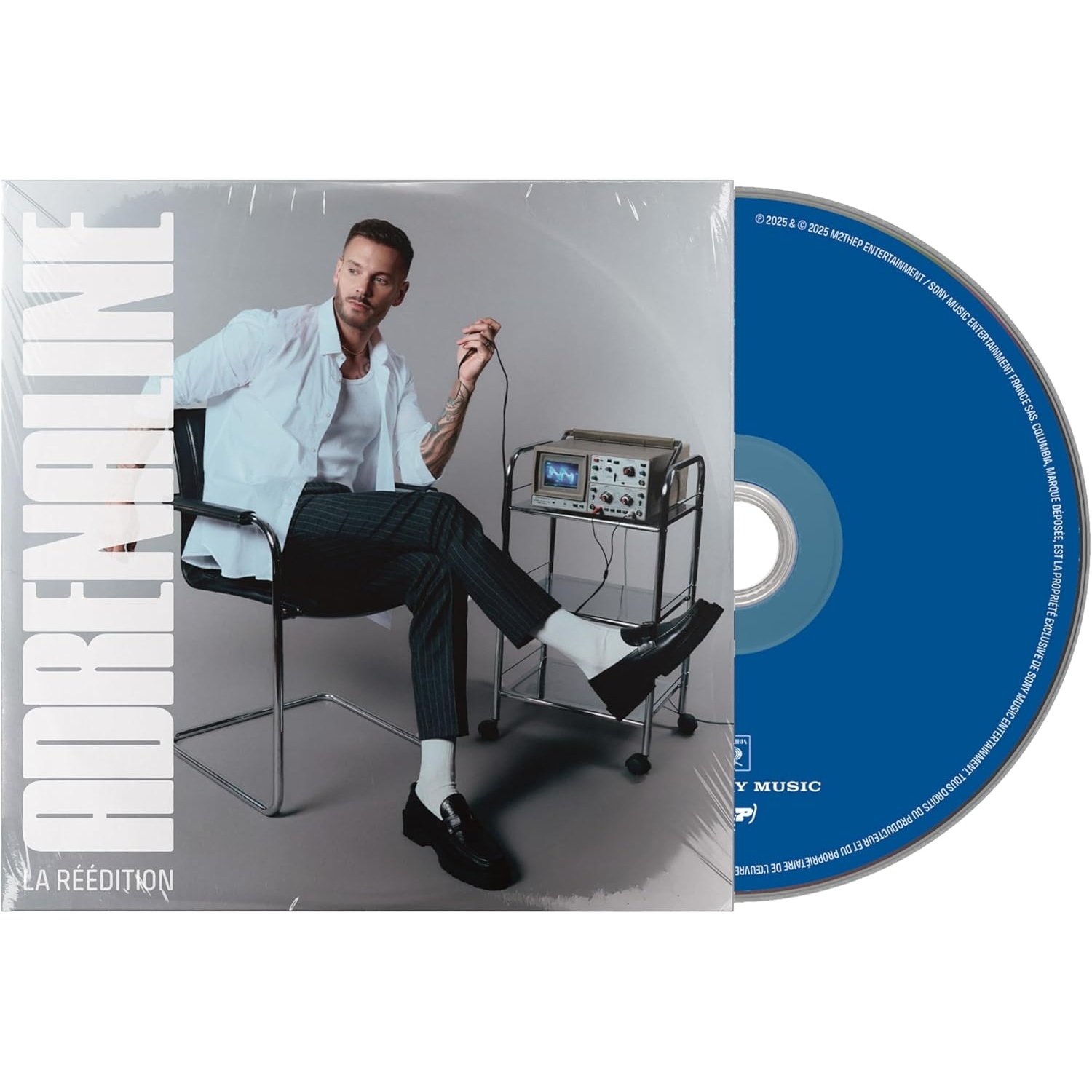 Man zit met album, houdt draad vast. Album leest 'ADRENALINE'. CD is blauw. Een machine staat naast hem.