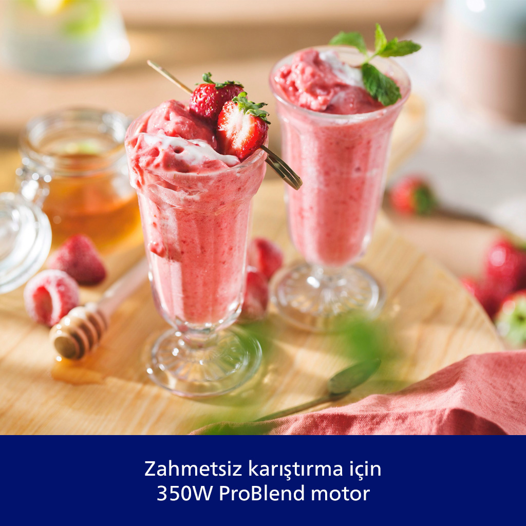 Uzun bardaklarda iki çilekli smoothie, çilek ve nane ile süslenmiş. Bal ve çilek de var.