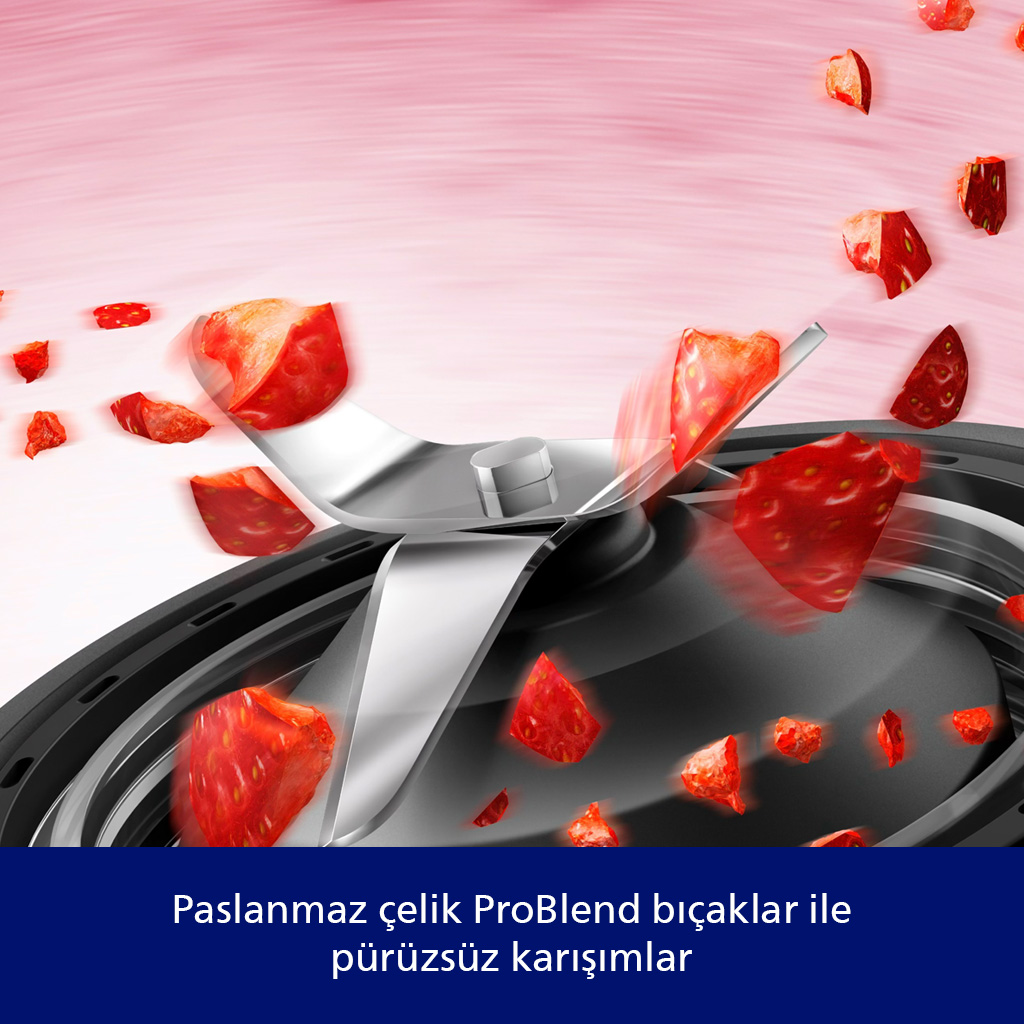 Paslanmaz çelik bıçaklı bir blender çilekleri kesiyor. Kırmızı meyve parçaları pembe bir arka plan üzerinde bıçakların etrafında dönüyor.