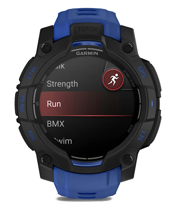 Smartwatch Garmin wyświetla opcje treningu: Siła, Bieganie, BMX i Pływanie. Zegarek jest czarny z niebieskimi akcentami i przyciskami.