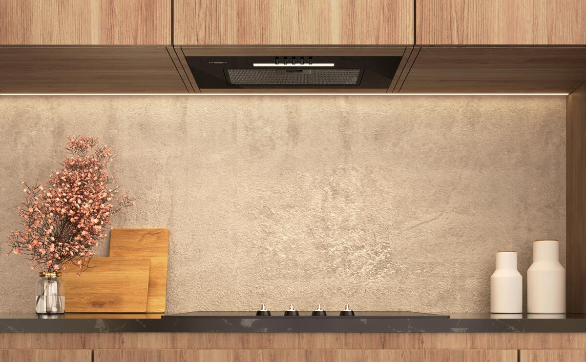 Wnętrze kuchni. Wyposażone w drewniane szafki, okap, blat, wazon z kwiatami i dwie białe butelki.