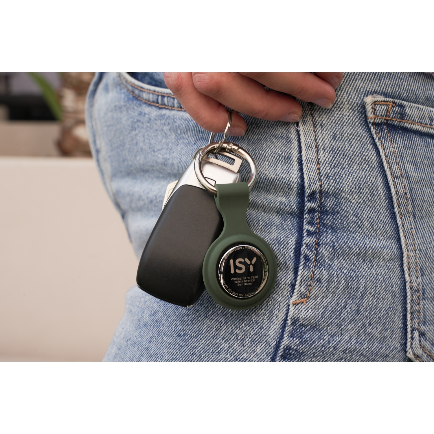 La mano di una persona tiene un portachiavi con chiavi dell'auto e un localizzatore ISY, vicino alla tasca di un paio di jeans.