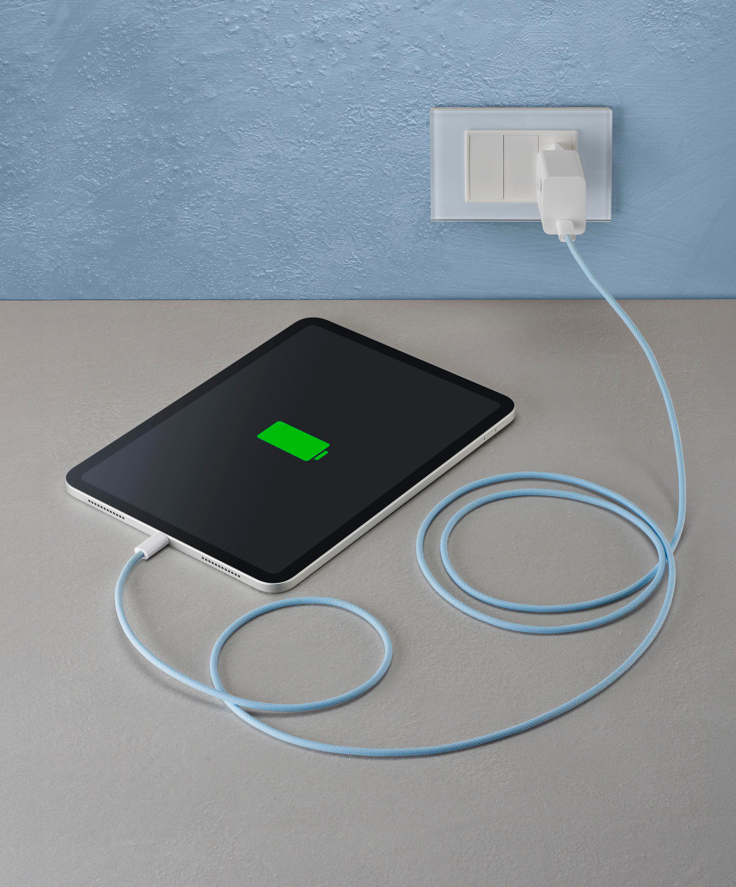 Tablet wird mit hellblauem Kabel aufgeladen. Auf grauer Oberfläche mit grünem Batterie-Symbol.