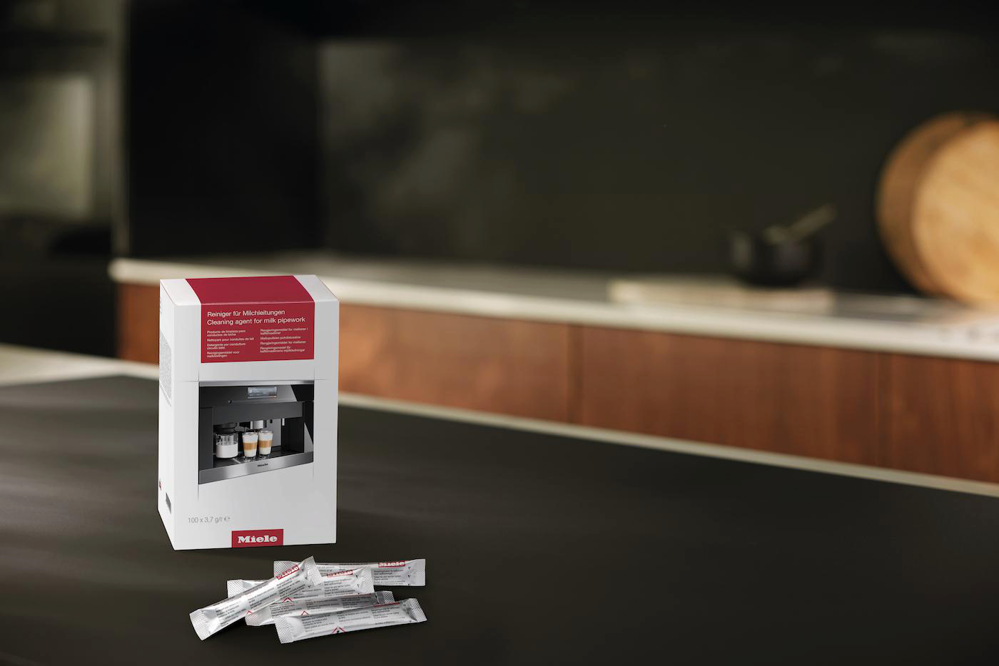 Eine Box mit Reinigungsmittel für Milchleitungen steht auf dunkler Oberfläche, daneben Päckchen des Reinigungsprodukts.