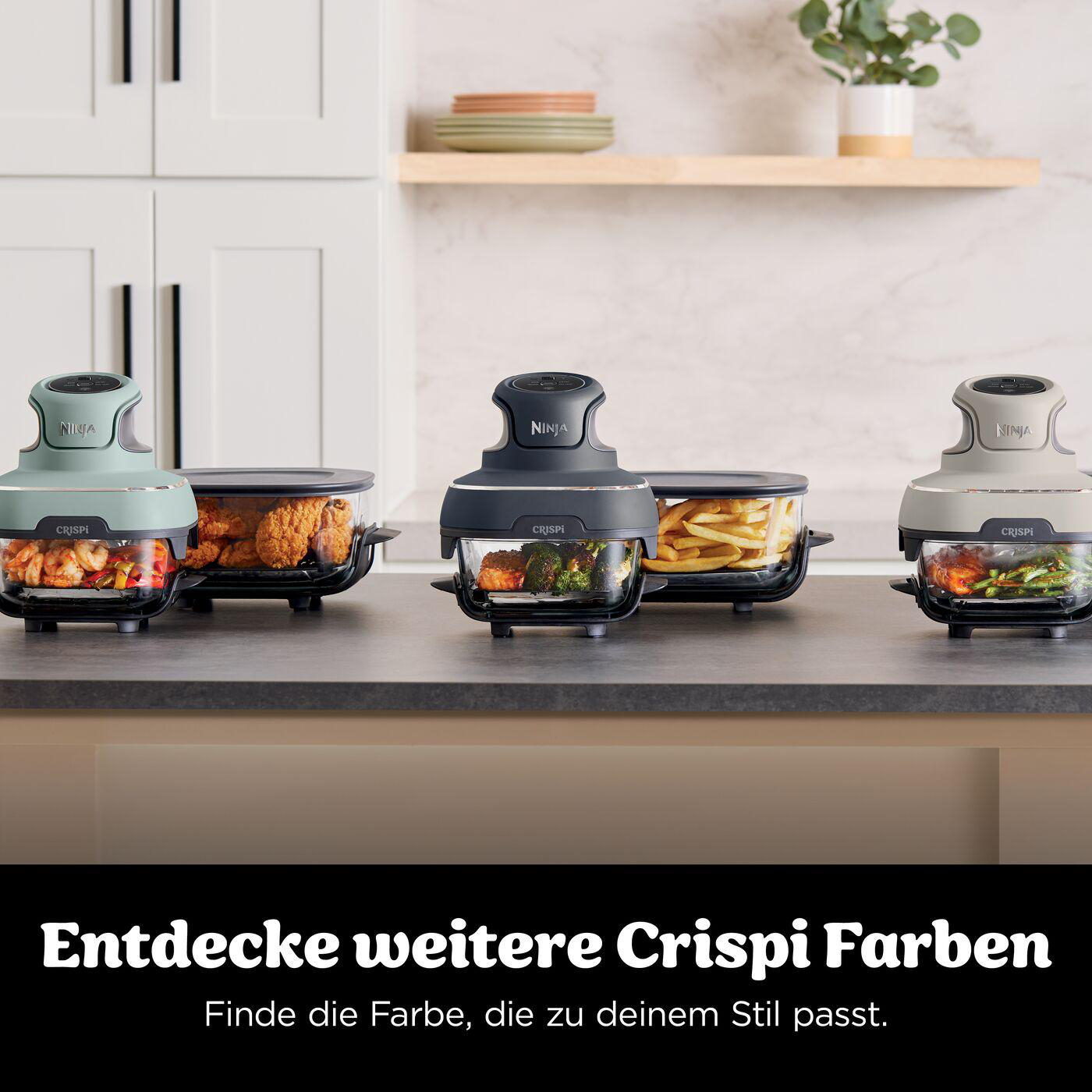 Drei Ninja Crispi-Heißluftfritteusen in verschiedenen Farben mit Essen, auf einer Küchenzeile platziert. Text darunter: 'Entdecke mehr Crispi Farben'.