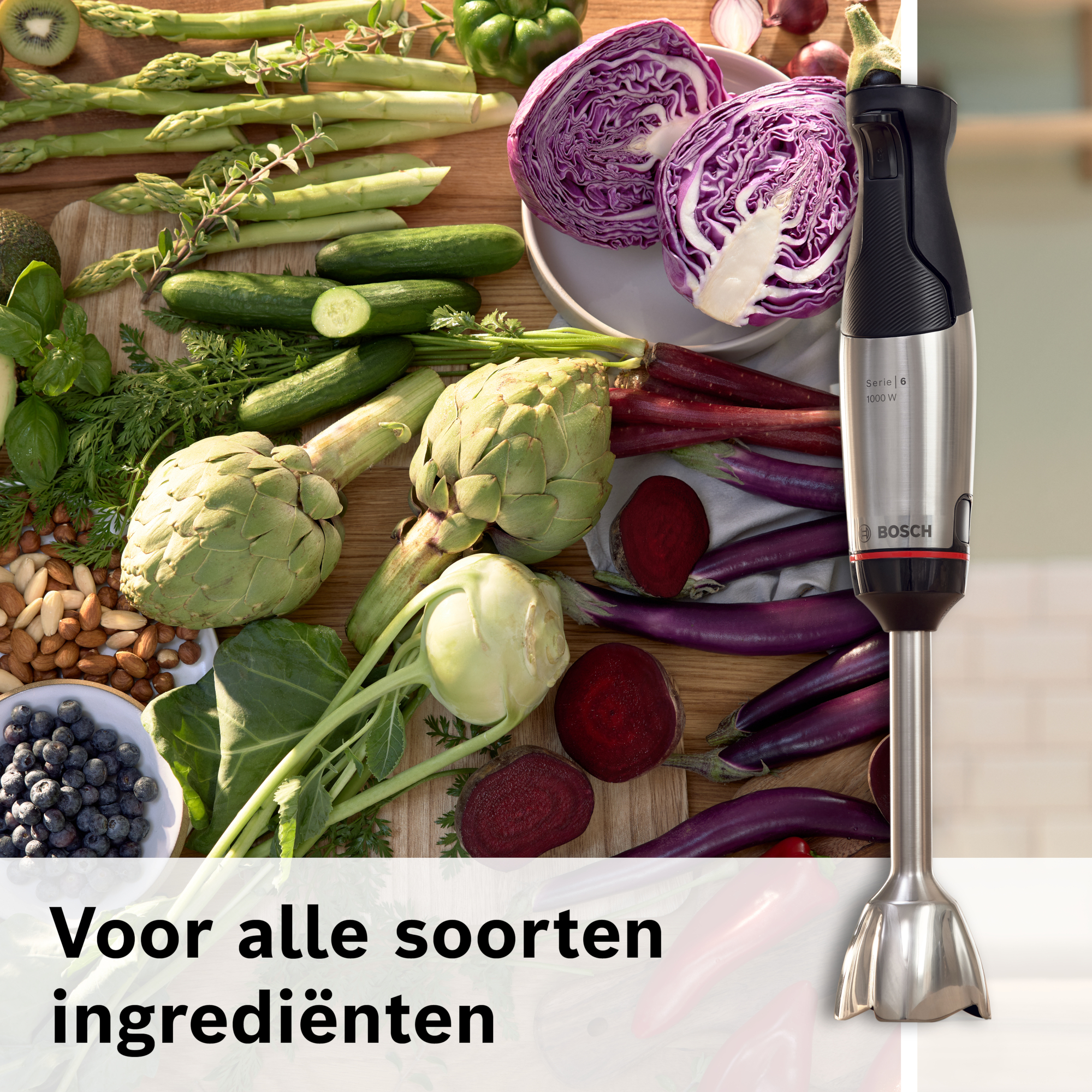 Afbeelding toont een Bosch staafmixer met diverse groenten, waaronder asperges, komkommers en rode kool, op een houten oppervlak.