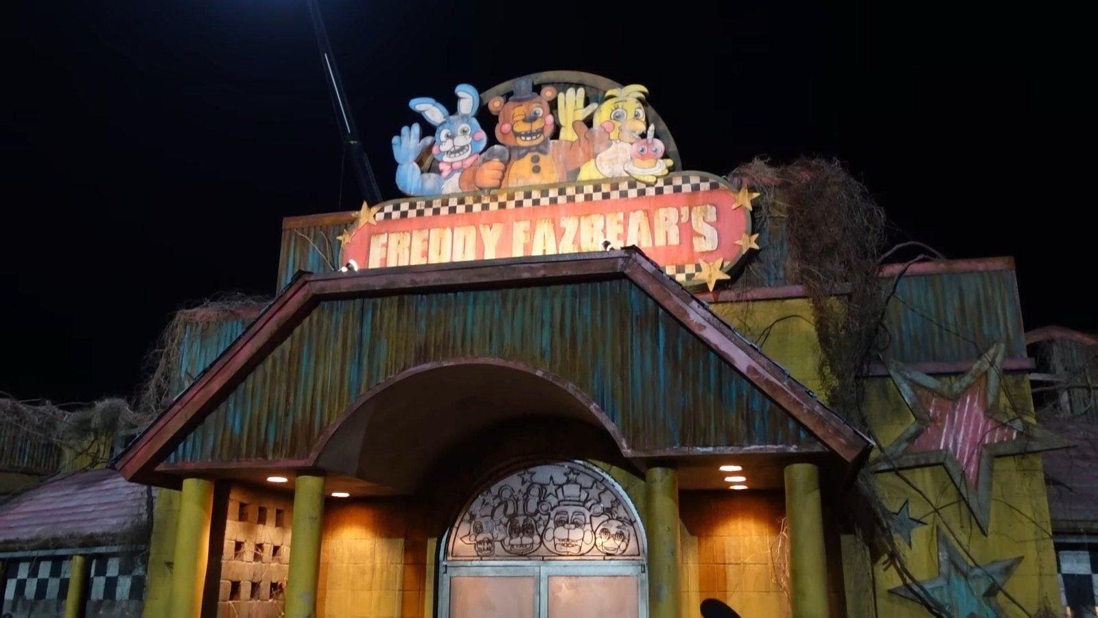 Schild von Freddy Fazbear mit animatronischen Figuren. Das Gebäude ist verwittert. Nachtkulisse.