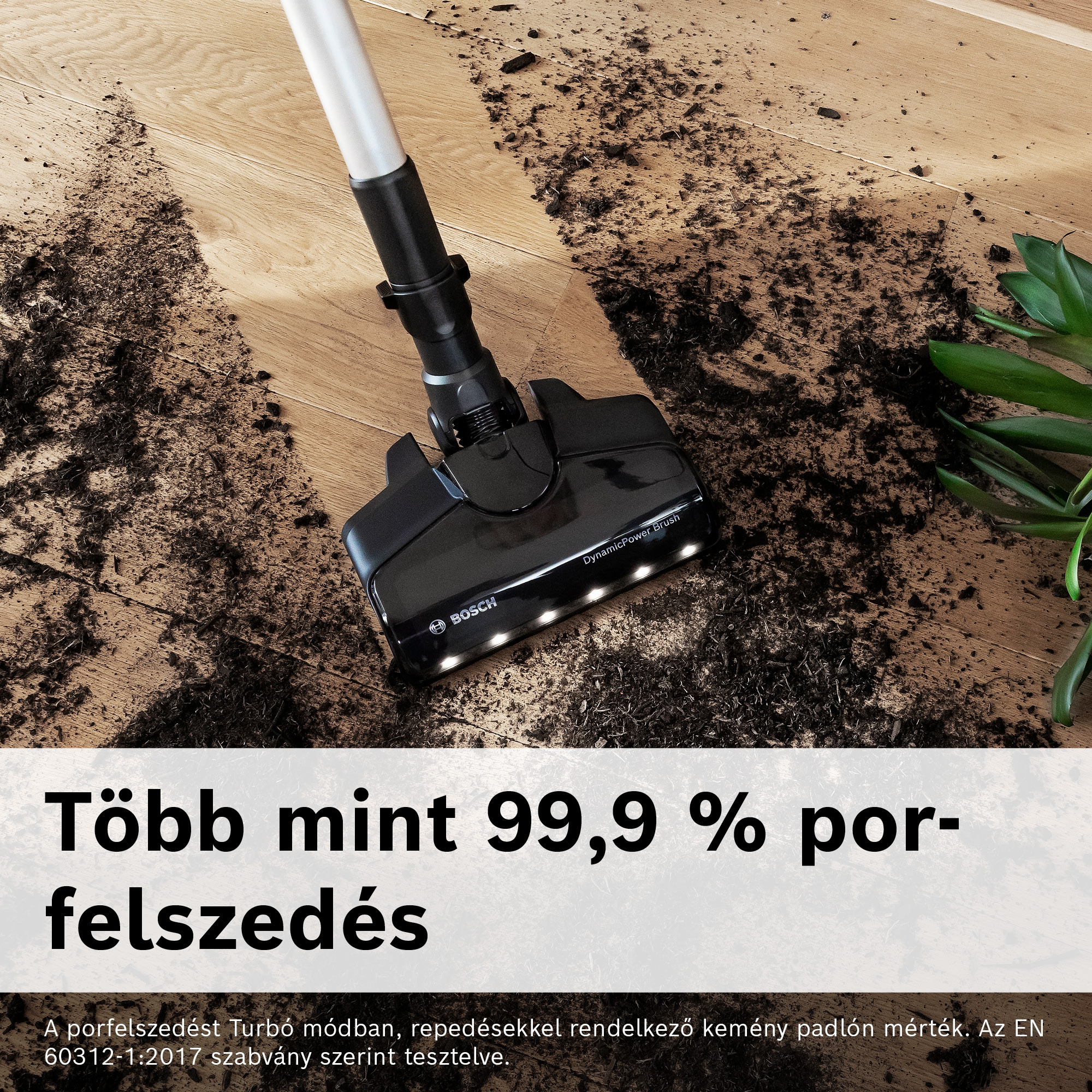 Egy fekete porszívófej tisztítja a szennyeződést egy fa padlón. Jobbra egy zöld növény van. Magyar nyelvű szöveg.