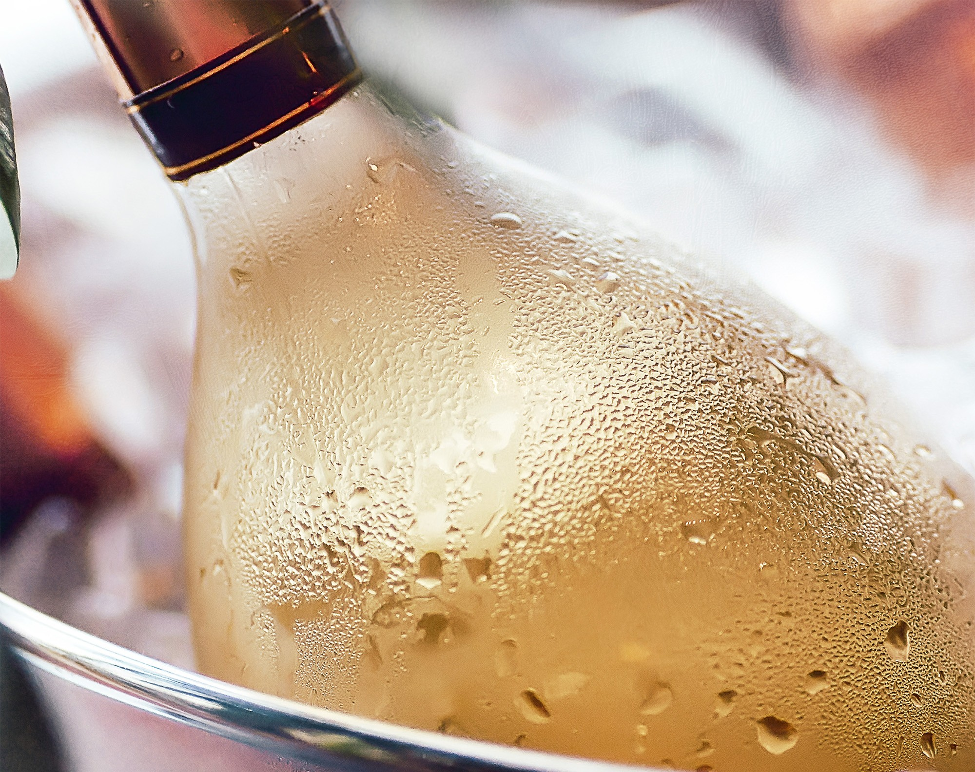 Primer plano de una botella de champán en una cubitera. La botella está húmeda con condensación.