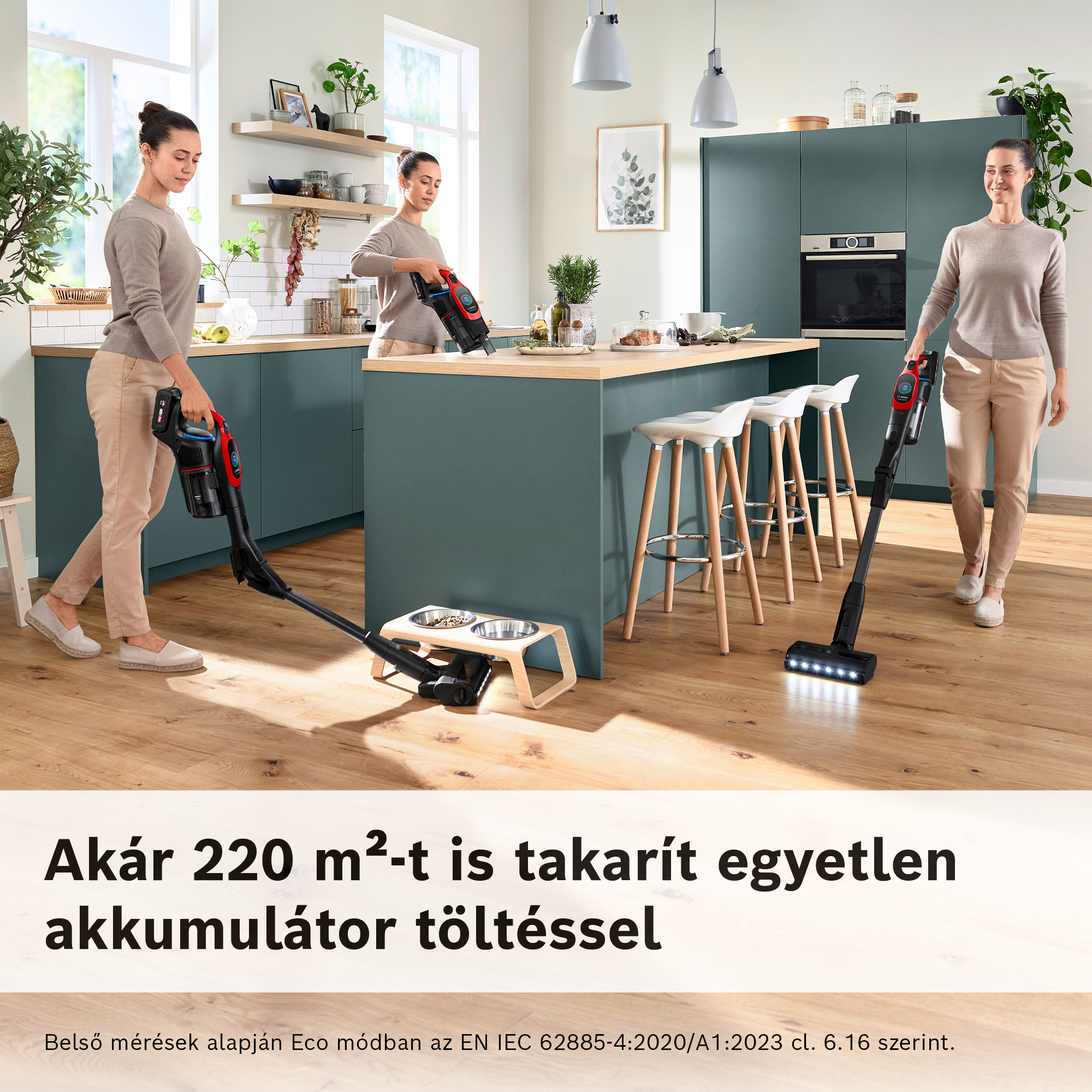 Három nő porszívózik egy konyhában. Egy kézi porszívót, kettő pedig botporszívót használ. A háttérben konyhaszekrények és egy pult láthatók.