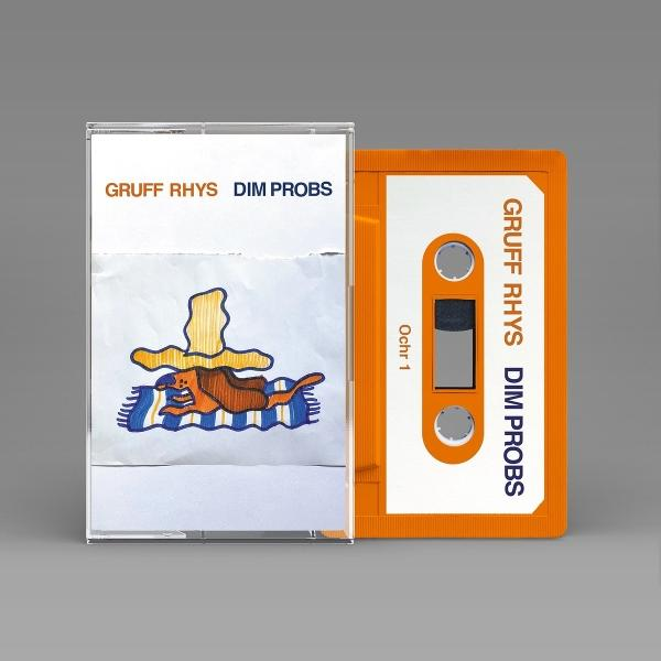 Eine orangefarbene Kassette neben einer Kassettenhülle. Auf Band und Hülle steht GRUFF RHYS DIM PROBS. Das Band hat eine Zeichnung.