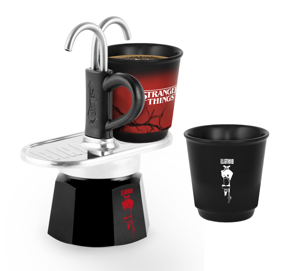 Schwarzer Moka-Kocher mit 'Stranger Things'-Tasse und schwarzer Tasse mit Logo. Kaffee ist in der 'Stranger Things'-Tasse.
