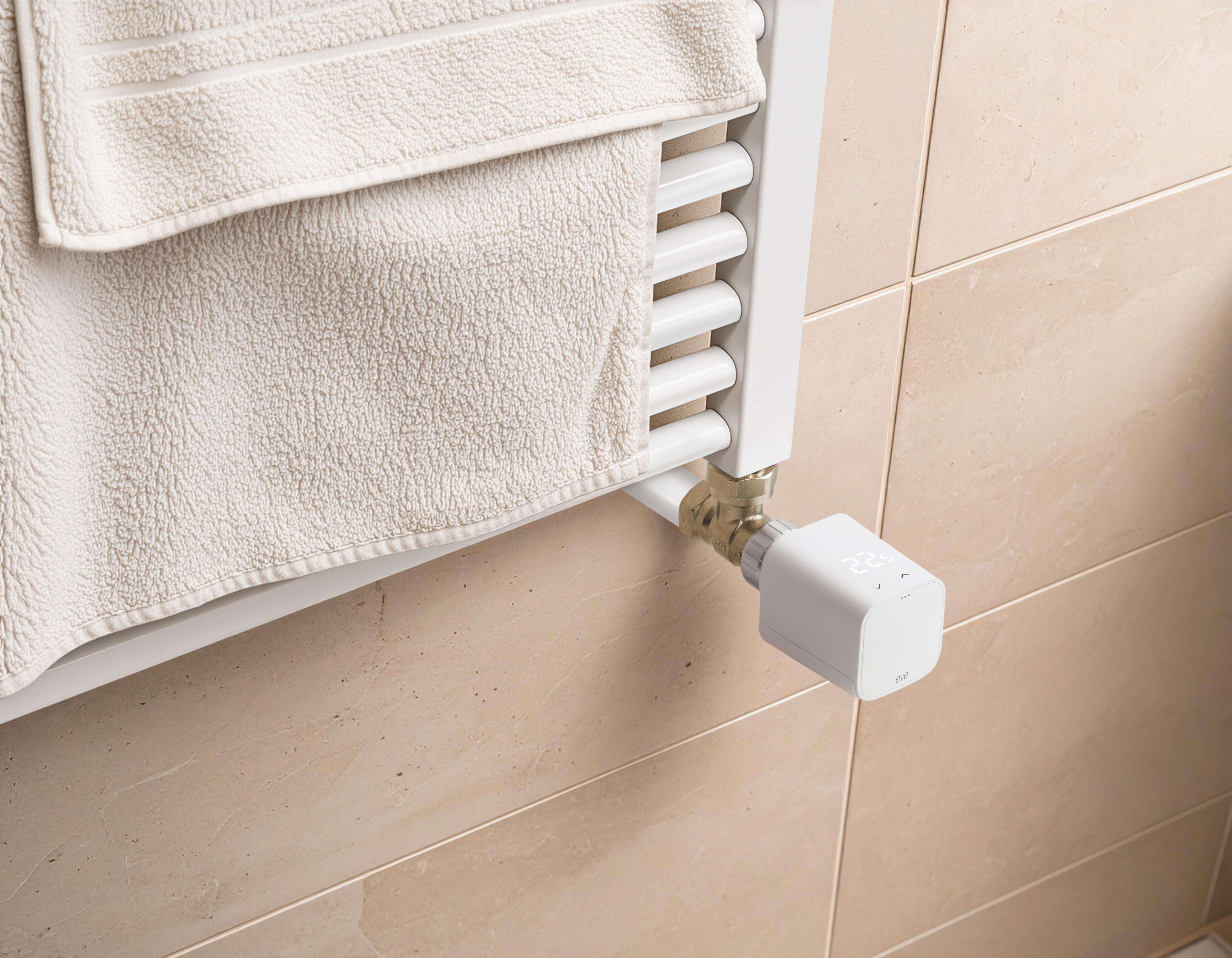 Ein weißer Heizkörper mit Handtuch und Smart-Thermostat. Beige geflieste Wand.