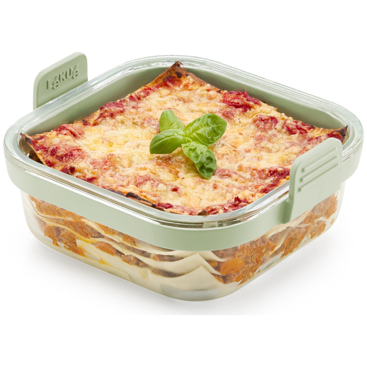 Lasagna in a green container. It has layers of pasta, sauce, and cheese, topped with basil. The container is on a white surface.