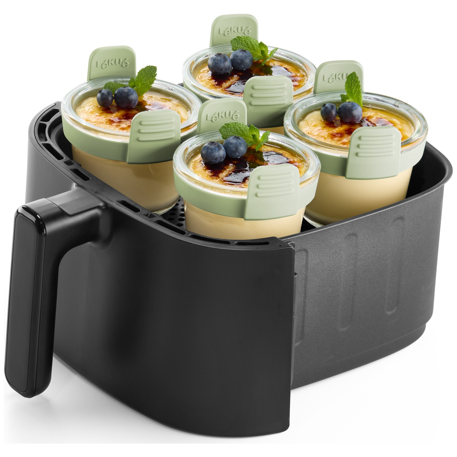 Vier crème brûlée-desserts in glazen potten met blauwe bessen en munt, in een zwarte airfryer.