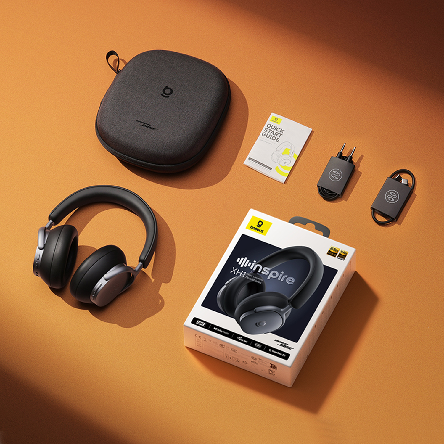 Auriculares supraaurales, estuche, guía de inicio rápido, cargador, cable y caja sobre una superficie naranja. La caja dice 'XH1 inspire'.