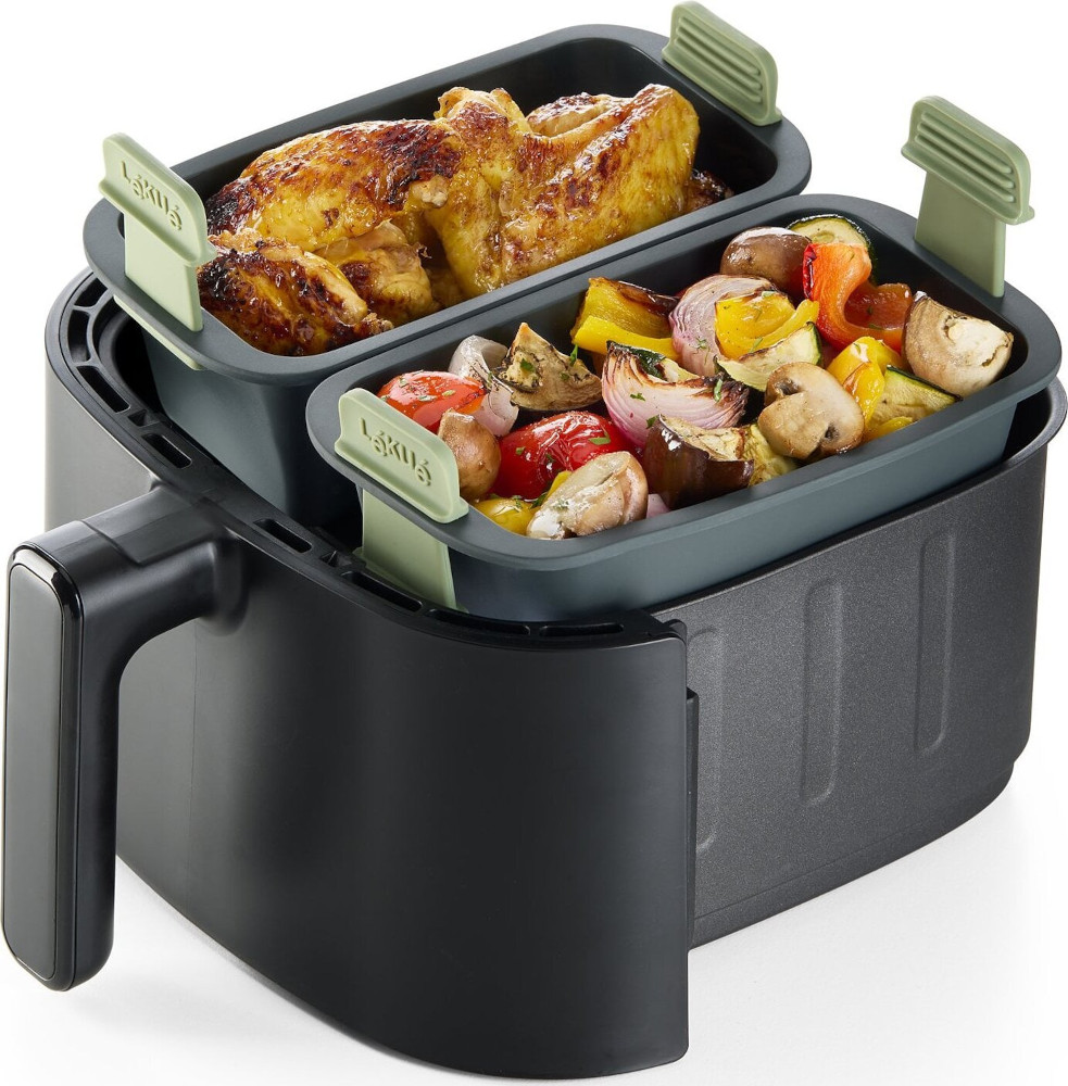 An air fryer with roasted chicken and vegetables in trays. The air fryer is black, and the trays have green handles.