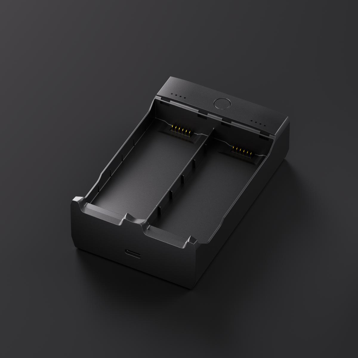 Ein schwarzes Dual-Slot-Batterieladegerät steht auf einer dunklen Oberfläche. Es verfügt über zwei Steckplätze, Kontrollleuchten und einen USB-Anschluss.