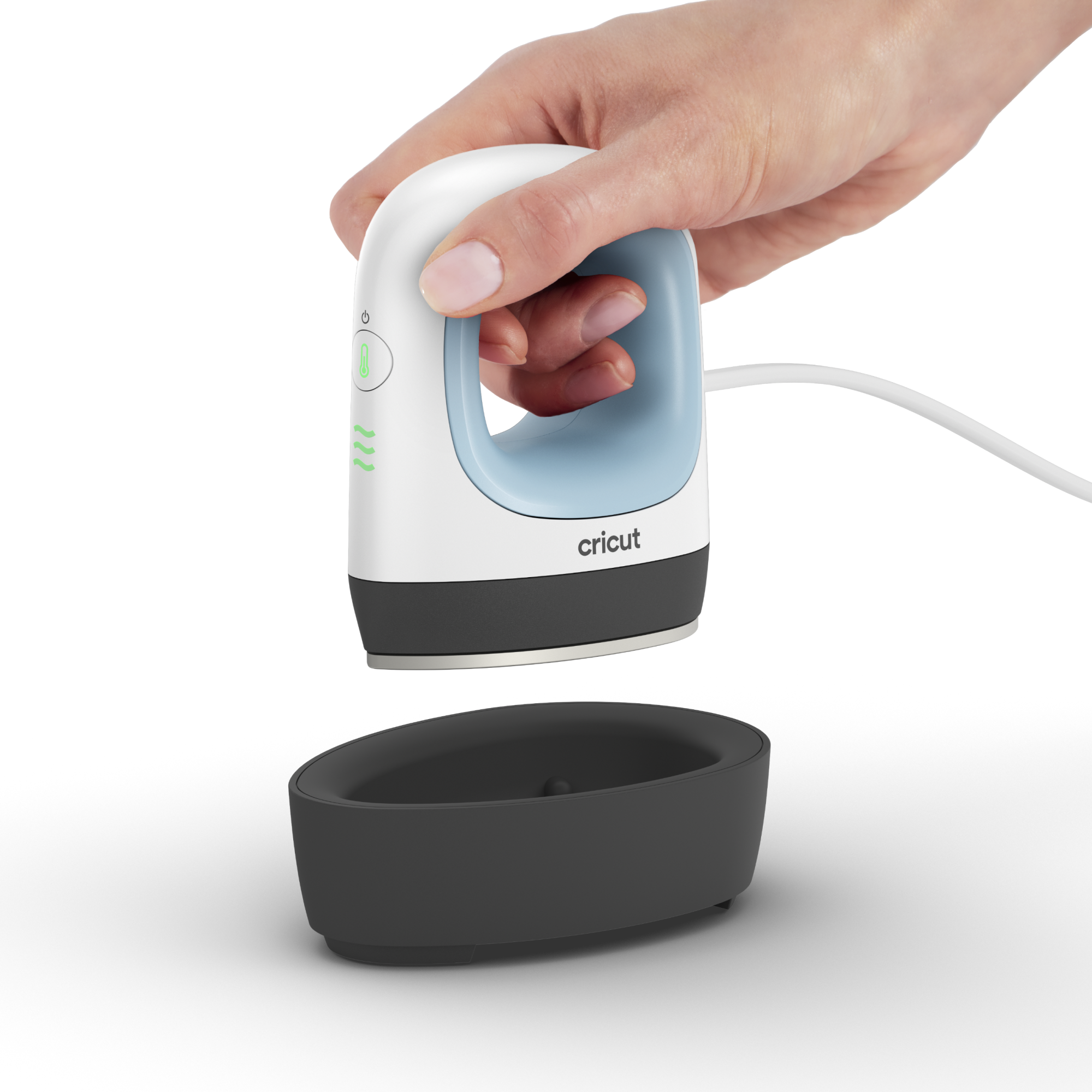 Ein weißes und blaues Cricut-Bügeleisen wird über einer schwarzen Basis gehalten. Eine Hand hält das Bügeleisen. Weißer Hintergrund.