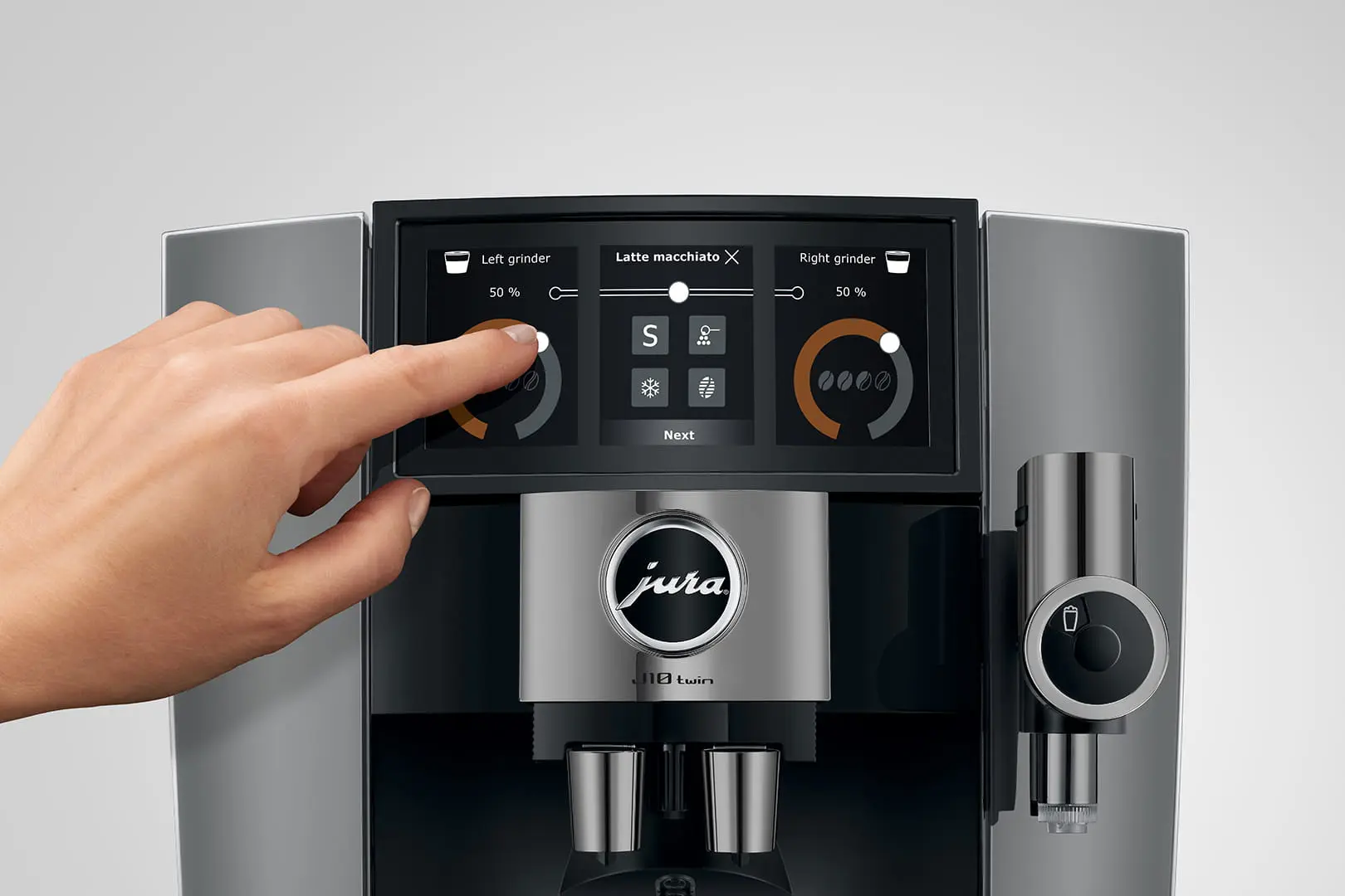 Eine Hand berührt den Bildschirm einer Kaffeemaschine. Es zeigt Mahleinstellungen und Getränkeoptionen. Die Maschine hat ein silbernes und schwarzes Design.