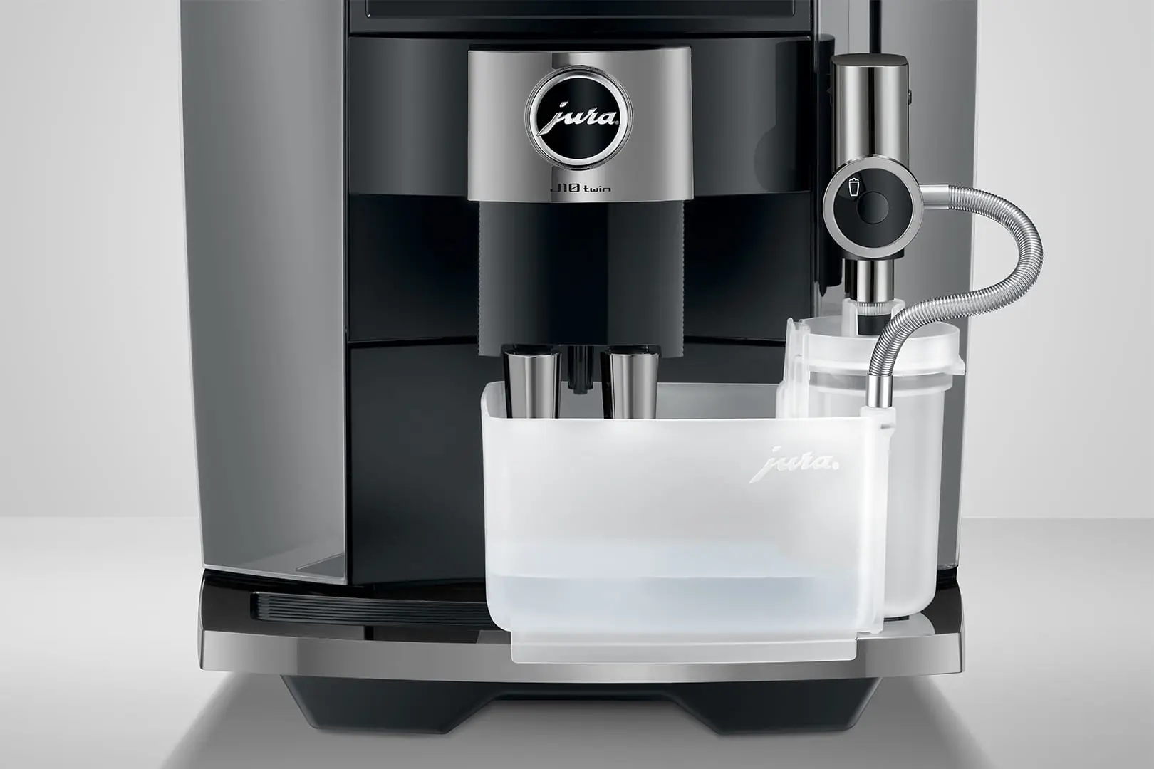 Eine Jura J10 Twin Kaffeemaschine. Sie ist schwarz und silber, mit einem Wasserbehälter und einem Milchaufschäumer. Das Jura-Logo ist sichtbar.