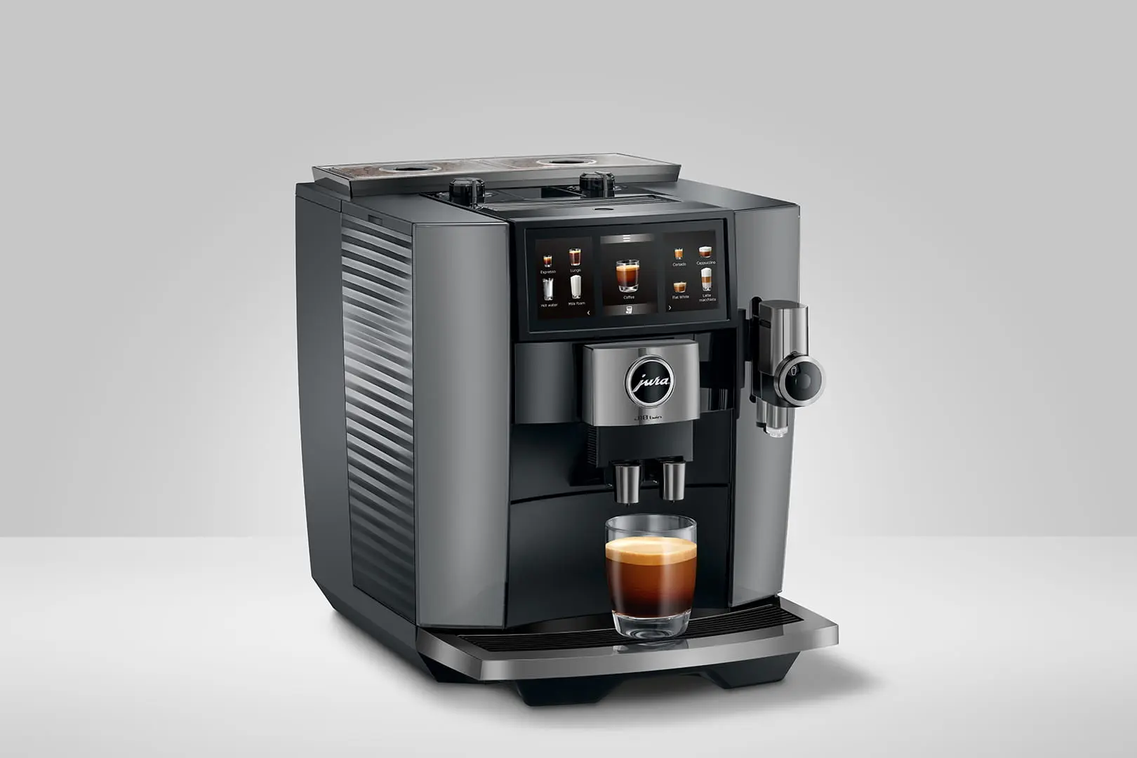 Eine Jura-Kaffeemaschine mit einem Glas Espresso. Die Maschine ist grau und schwarz mit Touchscreen.