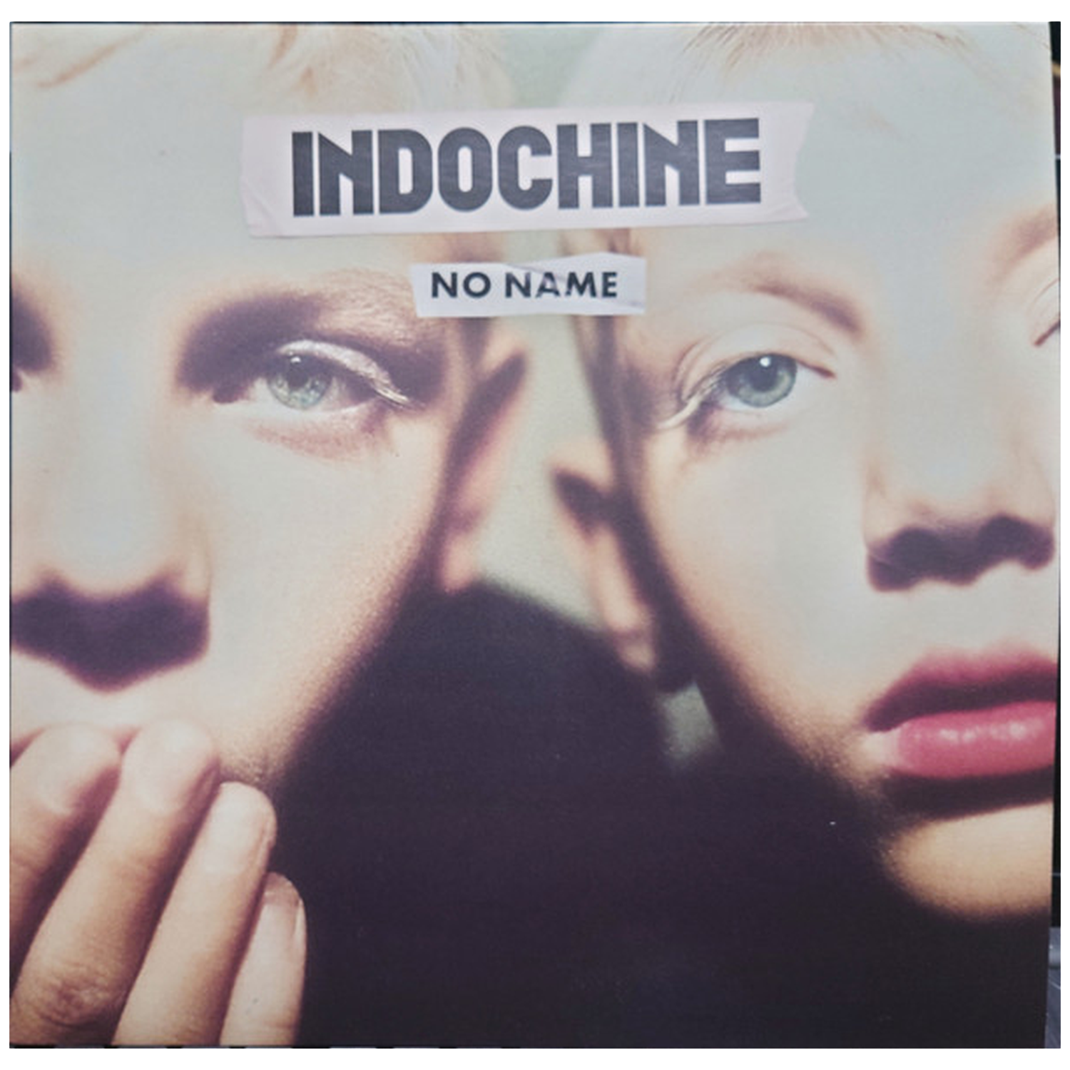 Albumhoes, Indochine, twee gezichten, lichte huid, blauwe ogen, roze lippen, tekst 'INDOCHINE' en 'NO NAME' op witte tape.