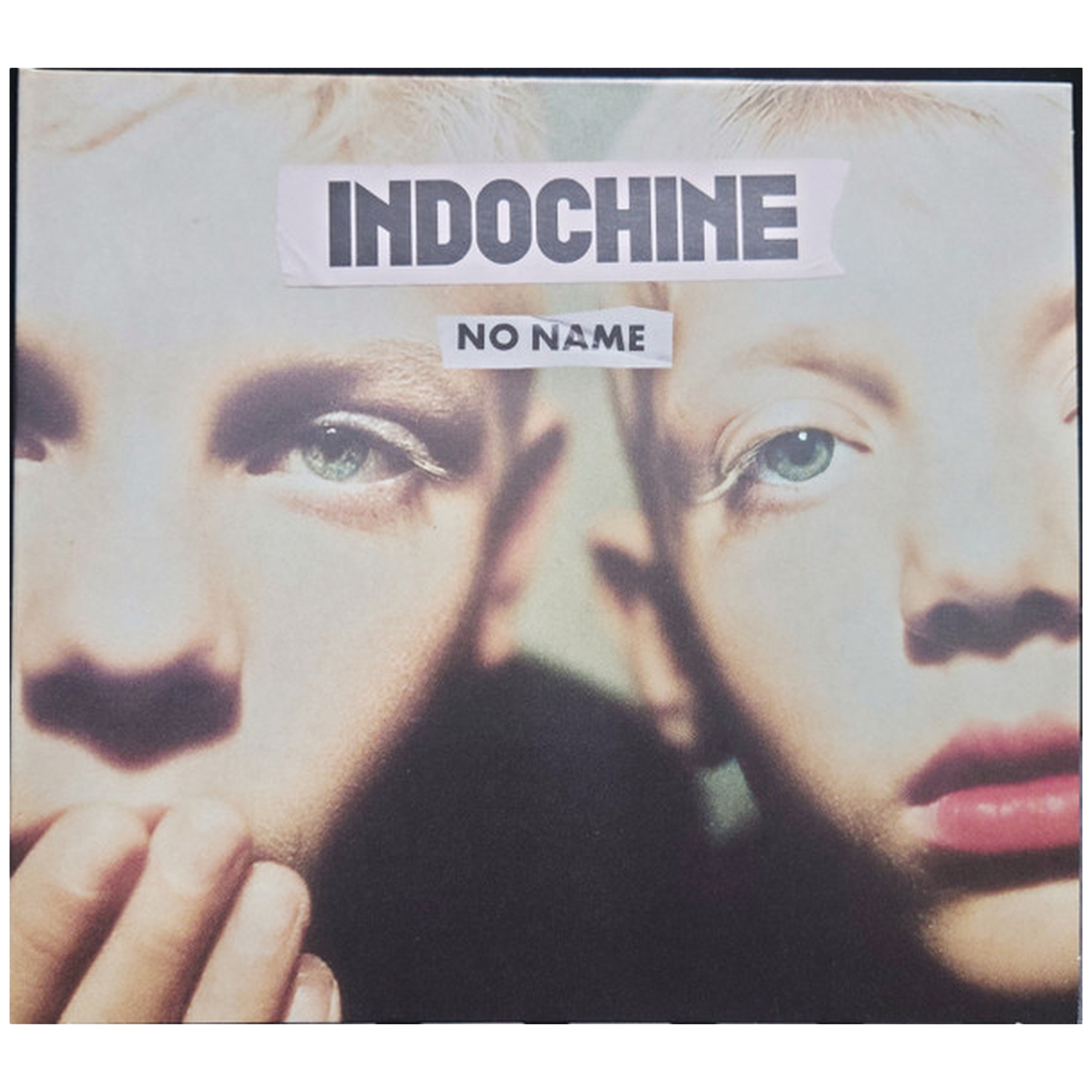 Albumhoes. Twee gezichten van een persoon met een lichte huid. Het woord 'INDOCHINE' staat bovenaan, 'NO NAME' in het midden.