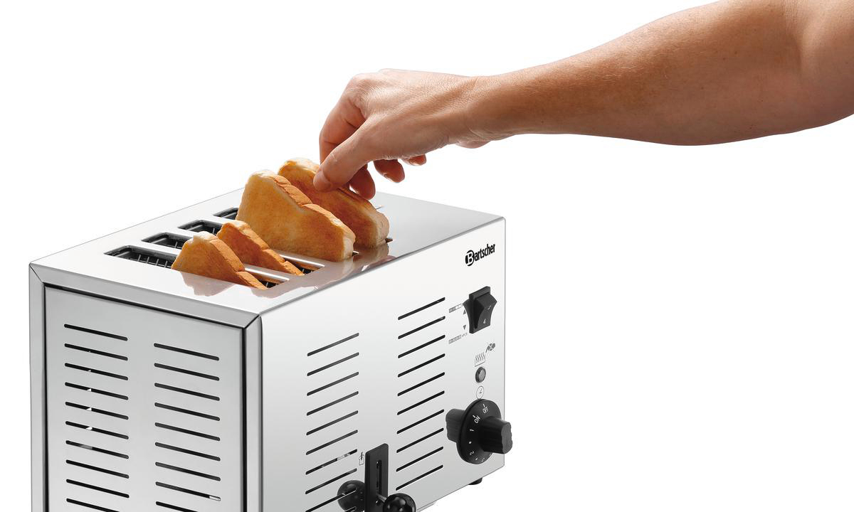 Eine Hand legt Toastbrot in einen silbernen Toaster. Der Toaster steht auf weißem Hintergrund. Einige Scheiben sind bereits drin.